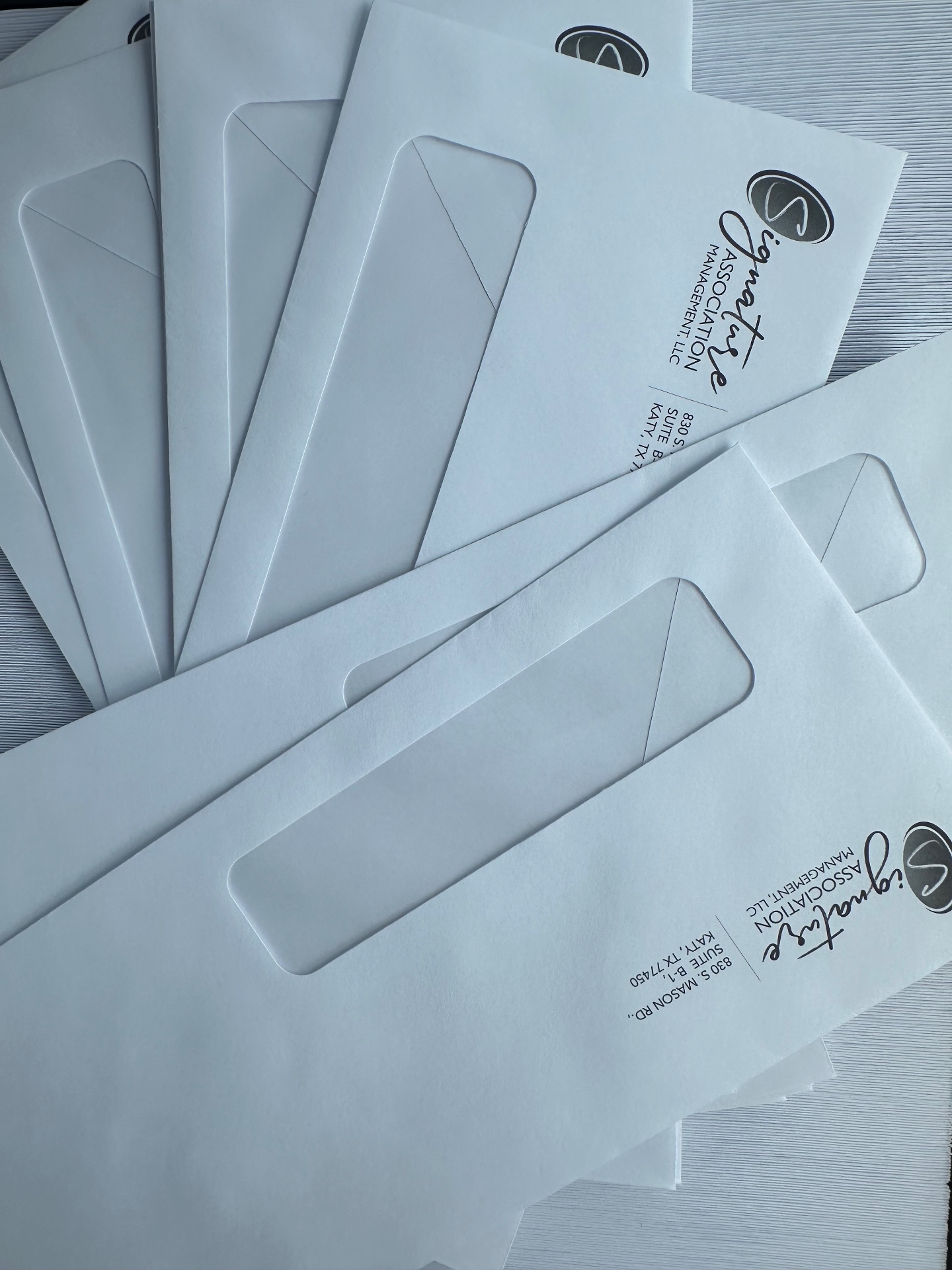 White branded envelopes arranged diagonally with printed logos and mailing details.